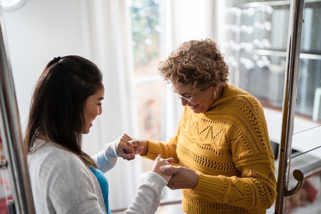 Nurse supporting senior patient walking or moving up the stairs at home